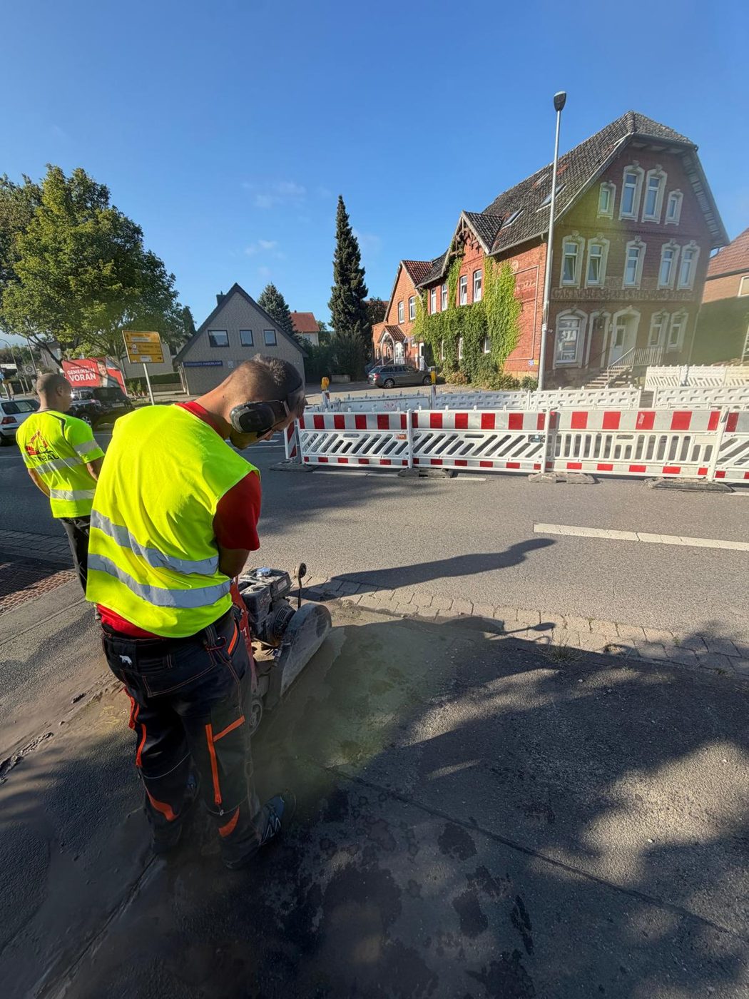 Bauarbeiter trennt den Asphaltbelag mit einem Fugenschneider